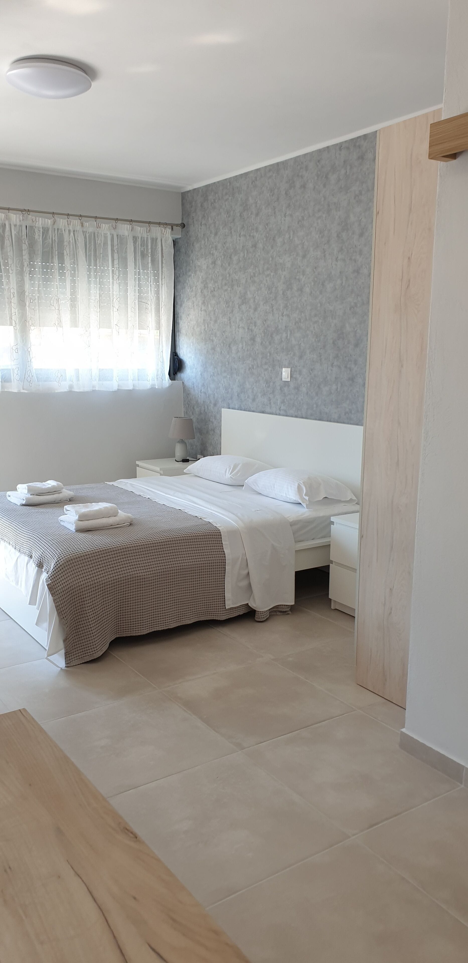 A bedroom with a bed, bedside tables, a lamp, and a window with curtains.