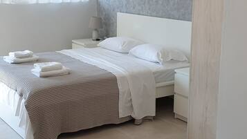 A bedroom with a bed, bedside tables, a lamp, and a window with curtains.