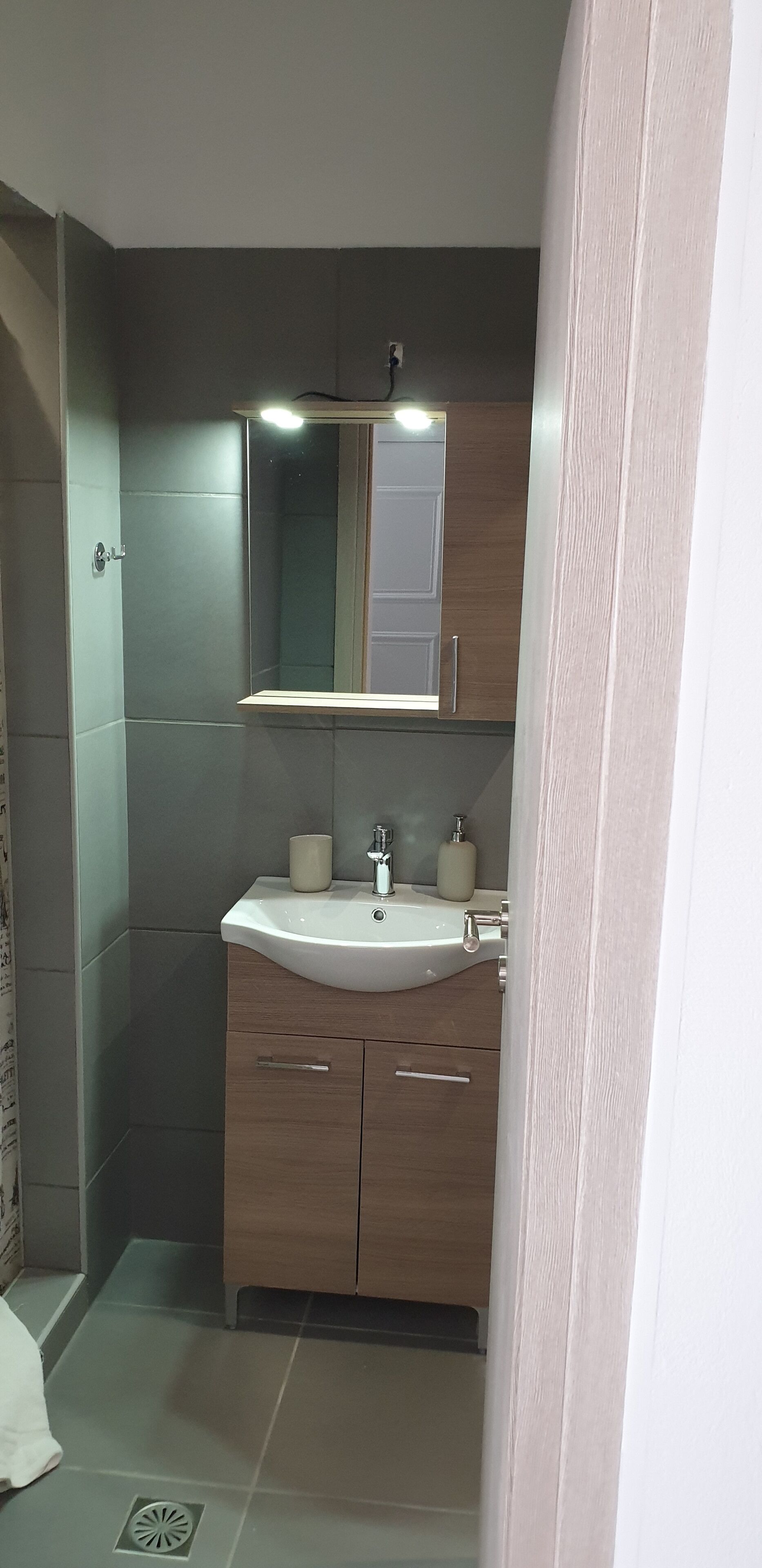 A bathroom with a white sink, wooden cabinets, a mirror, and a light fixture.