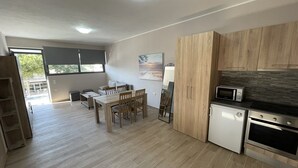 A modern kitchen with wooden cabinets, a dining area with a table and chairs, a small refrigerator, and a microwave. - AVR DELUXE SUITES 6 AIRPORT FREE SHUTTLE (Markopoulo Mesogaias)