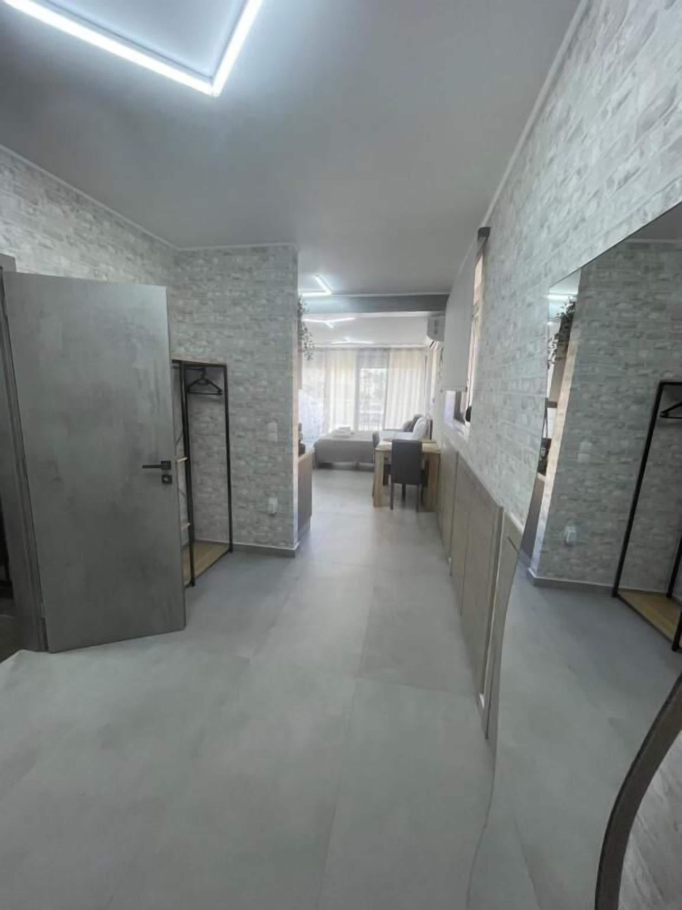 A hallway with a bed, a desk, and a chair in the background.