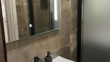 A modern bathroom with a white sink, black faucet, and a mirror with a black frame.