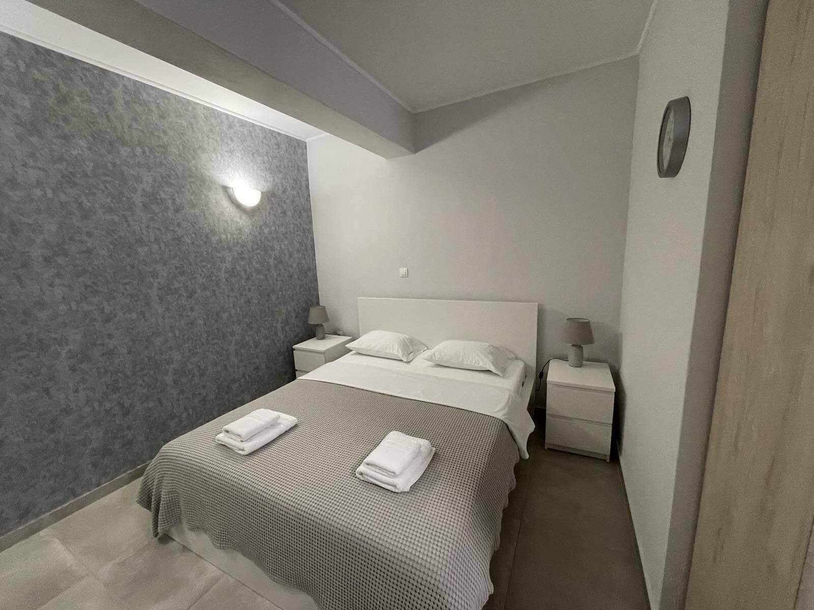 Une chambre d’hôtel moderne avec un grand lit, deux tables de chevet et une petite table d’appoint.