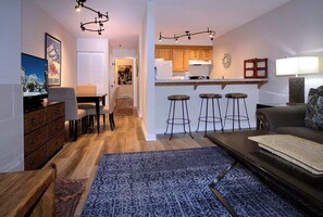 Eine moderne Küche mit Holzschränken, einem Kühlschrank und einer Bar mit Hockern.