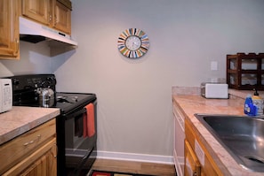A kitchen with wooden cabinets, a stainless steel sink, a microwave, and a colorful clock on the wall. - Escape to Emmons, Ski in/Ski out, Hot tub (Mt Crested Butte)