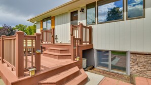 A two-story house with a wooden deck and a stone wall.