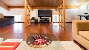 A spacious living room with a wooden ceiling, a large flat-screen TV, and a glass coffee table with chocolates. - Villa Coco - 10 Guests, Stunning Mt Etna Views (Castiglione di Sicilia)