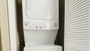 Une petite buanderie équipée d’un lave-linge et d’un sèche-linge à chargement frontal, d’une porte blanche et d’un plancher en bois.