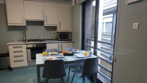 A compact kitchen with a dining table set for breakfast, a microwave, and a gas stove. - Em-charming Apartment (Ponta Delgada)