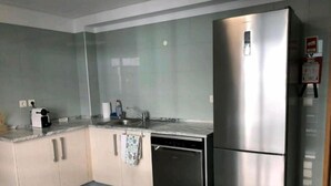 A modern kitchen with a stainless steel refrigerator, a dishwasher, and a marble countertop. - Em-charming Apartment (Ponta Delgada)