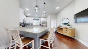Een moderne keuken met een centraal eiland, witte kastjes en een eethoek van hout.