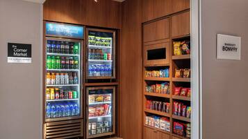A corner market with refrigerated beverage dispensers and shelves stocked with snacks and beverages.