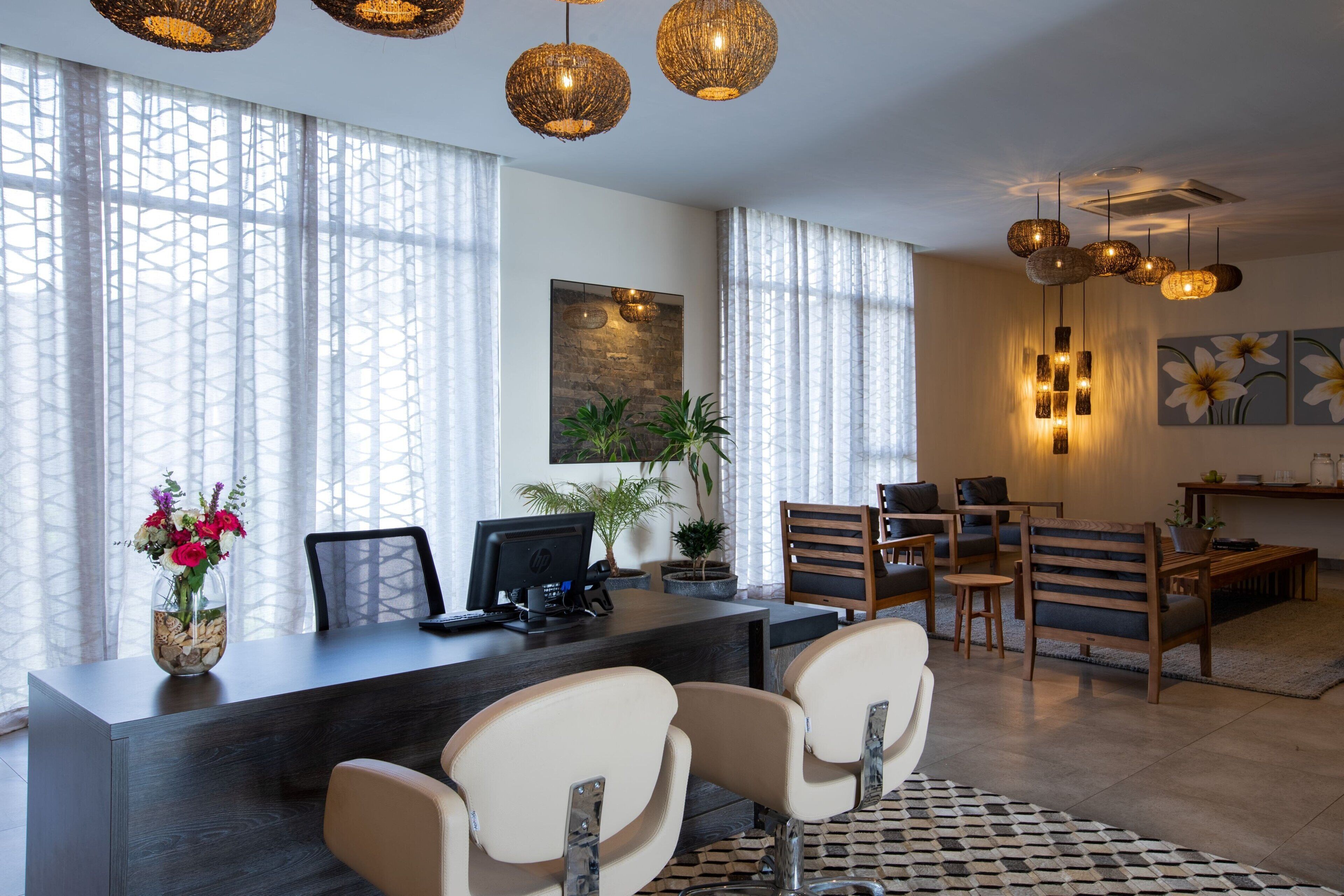 A modern reception area with a desk, chairs, and a large window with sheer curtains.
