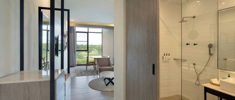 Un baño moderno con cabina de ducha de vidrio, un tocador con espejo y vistas a un patio exterior.