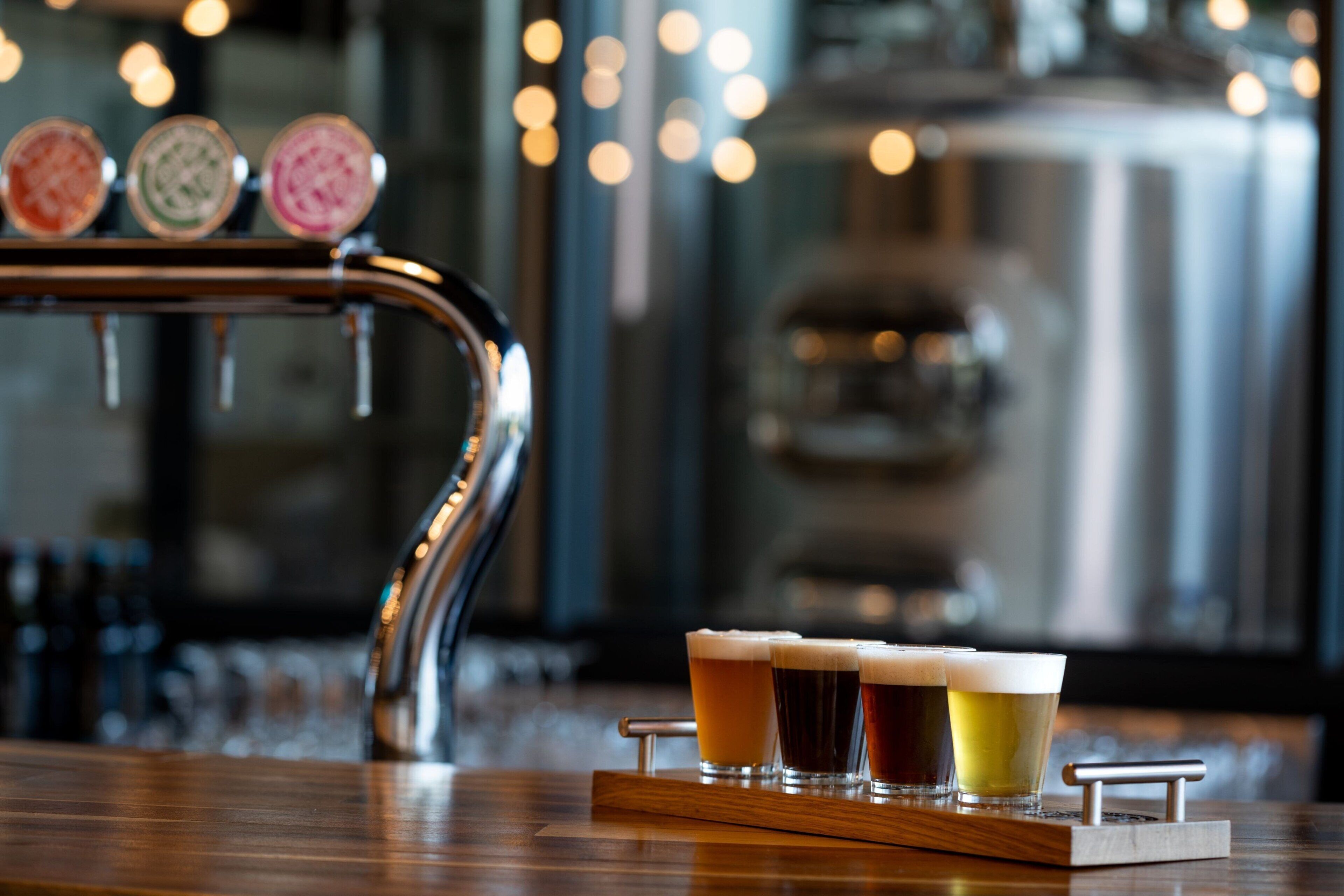 A bar area with a tap and glasses of beer on a wooden tray.