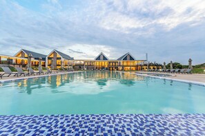 A swimming pool with lounge chairs and a building with multiple sections in the background. - Ciêla, Lusaka, a Tribute Portfolio Resort and Spa (Lusaka)