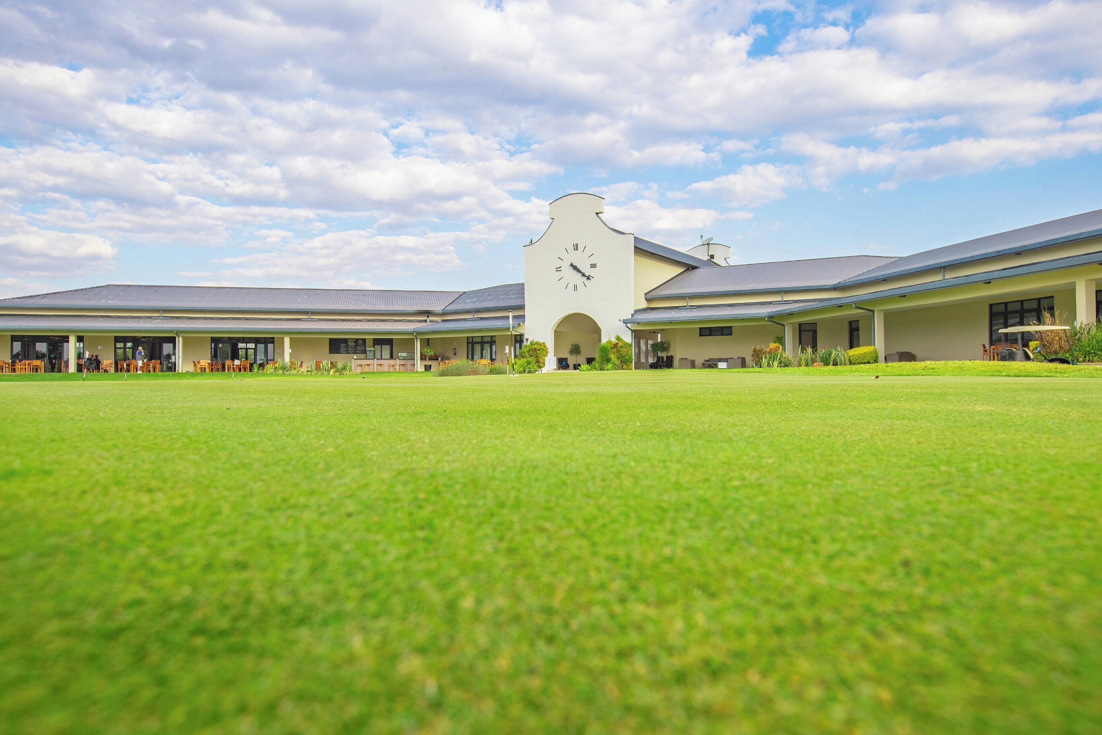 A building with a clock tower, a large lawn, and multiple covered areas.