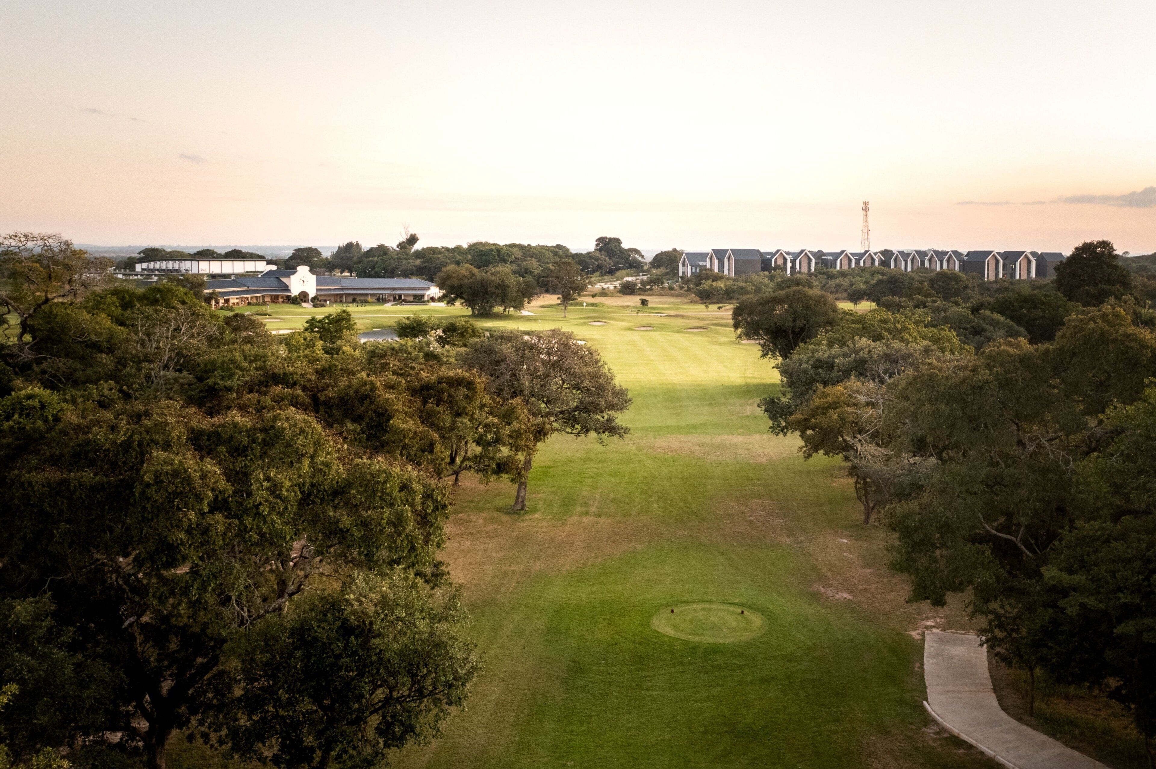 Un parcours de golf doté d’un club-house, d’arbres et offrant une vue sur un ciel dégagé.