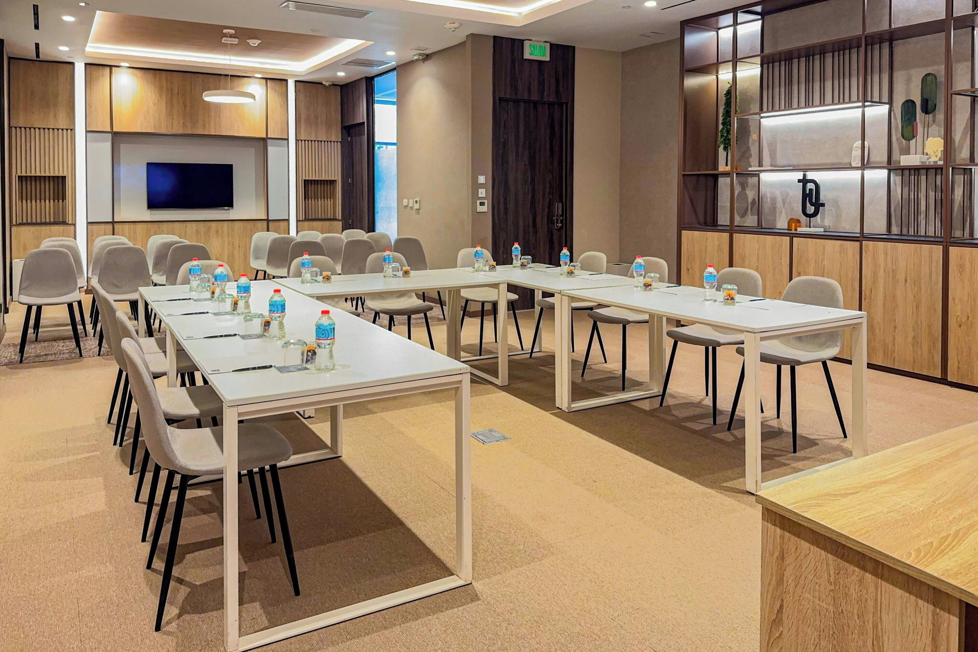 A conference room with multiple tables and chairs, equipped with water bottles and nameplates.