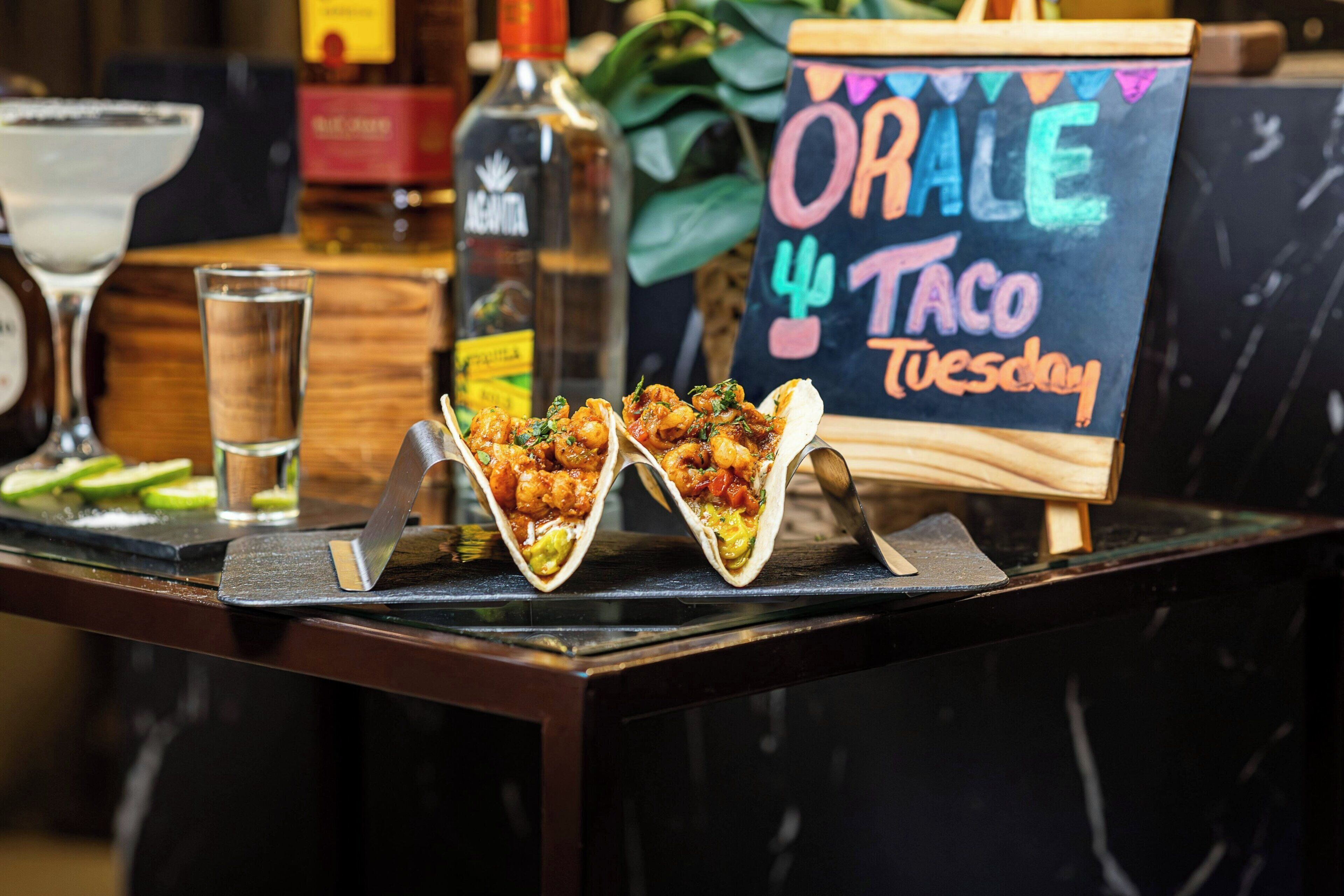 Een taco kraam met een schoolbord waarop staat aangekondigd: 'ORAL TACO Dinsdag'.