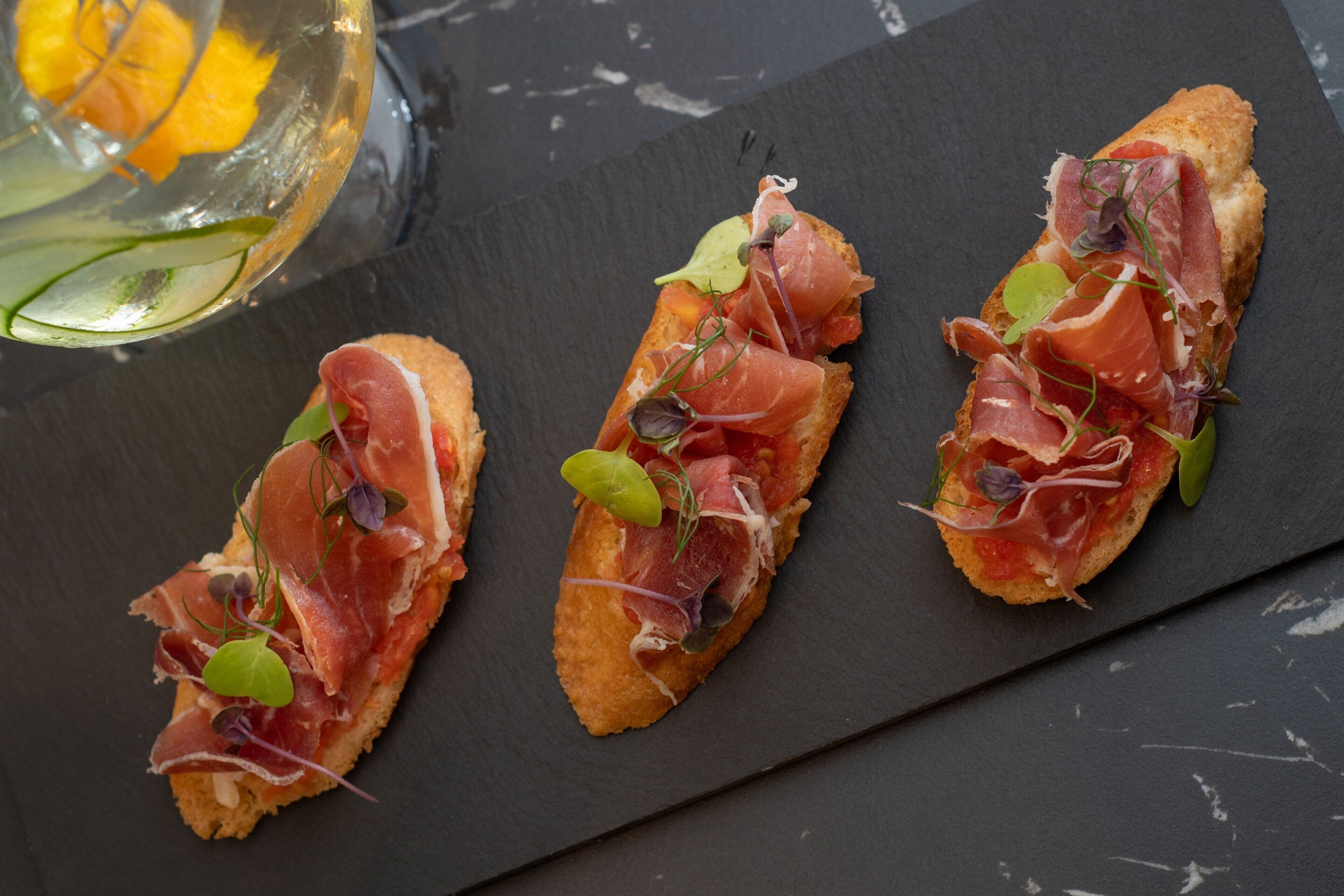 Tres bruschettas sobre una tabla de pizarra.
