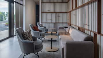 Eine moderne Lobby mit Sitzgelegenheiten, einem Couchtisch und Blick durch große Fenster.