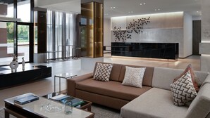 Una sala de estar moderna con sofá, mesa de centro y chimenea. Hay un ventanal y vistas a zonas verdes.