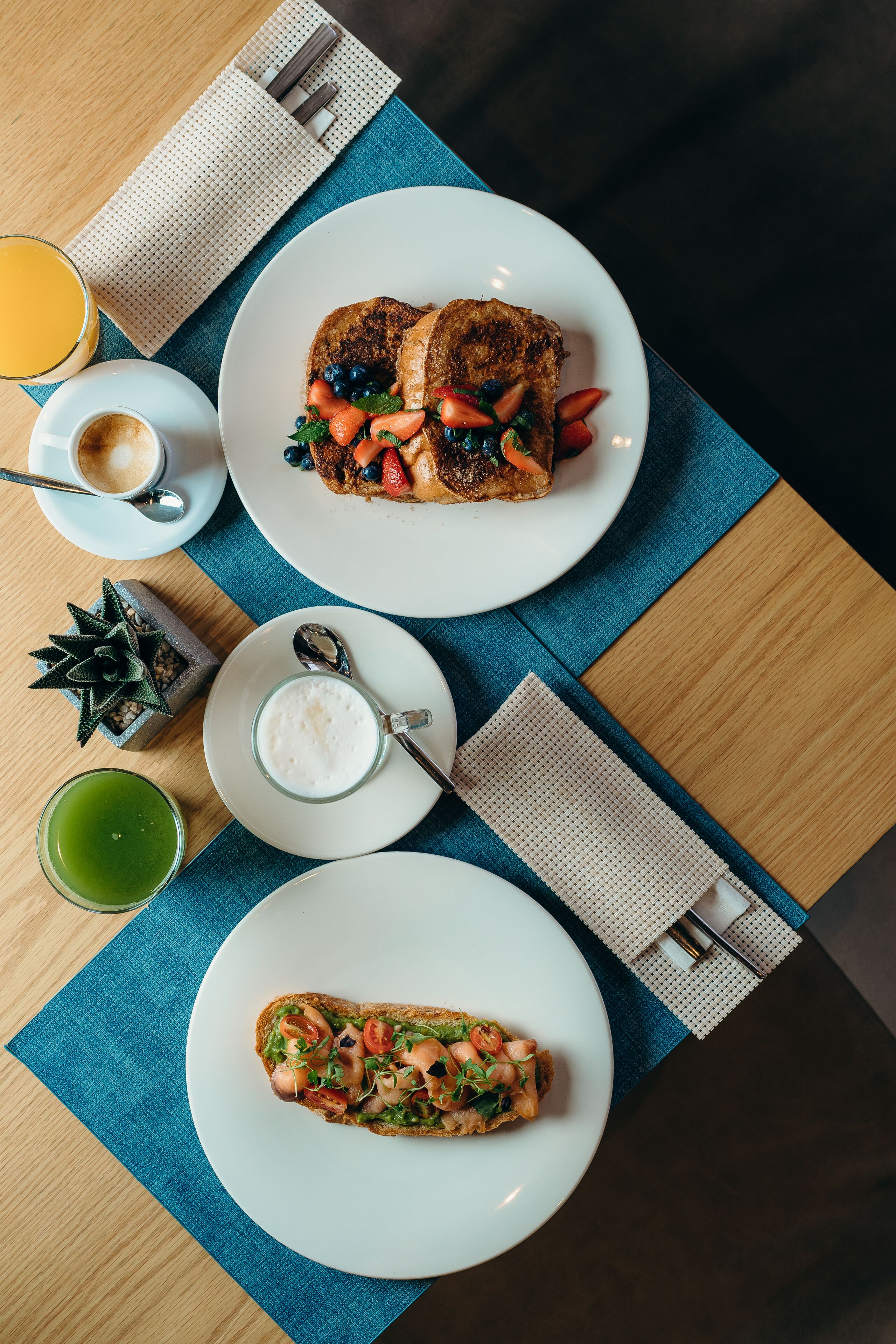 Een ontbijt met toast, een kop koffie en een glas sinaasappelsap op een houten tafel.