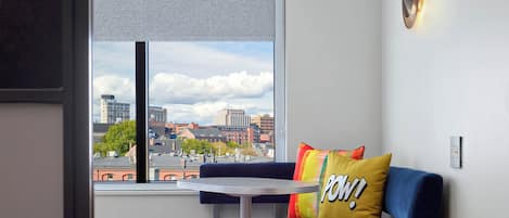 A modern room with a sofa, a small round table, and a window offering a city view.