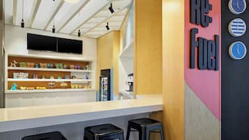 A modern kitchen with a white countertop, black stools, and a large clock on the wall.