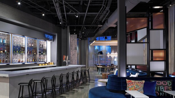 A modern bar area with a bar counter, seating, and a view of the cityscape. - Aloft by Marriott Portland Downtown Waterfront ME (Portland)