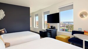 A hotel room with two beds, a TV, a desk, and a view of the city. - Aloft by Marriott Portland Downtown Waterfront ME (Portland)