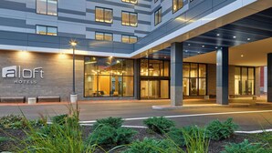 A modern hotel entrance with a glass facade, outdoor seating, and a well-lit lobby area. - Aloft by Marriott Portland Downtown Waterfront ME (Portland)