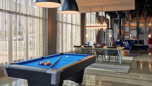 A pool table with balls, a sofa, and a dining area with chairs and tables. - Aloft by Marriott Portland Downtown Waterfront ME (Portland)