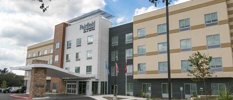 Un hotel Fairfield by Marriott con diseño moderno, que presenta una entrada destacada, varios pisos y un área de estacionamiento.