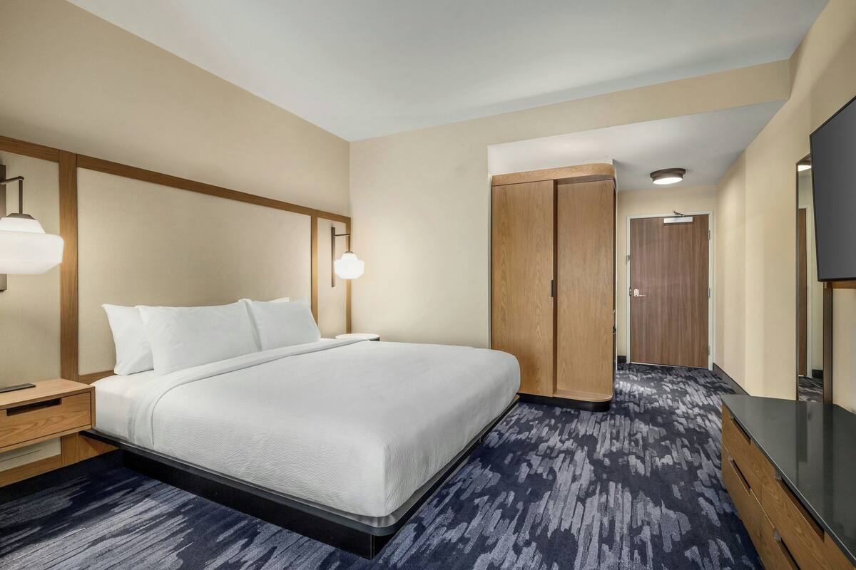 Une chambre d’hôtel avec un grand lit, une armoire en bois, un bureau et un téléviseur à écran plat.