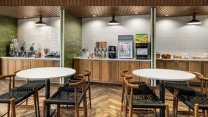 Un café moderne avec des meubles en bois, des tables blanches et un mur en briques.