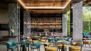 A modern bar area with marble walls, a variety of seating options, and a well-stocked liquor display. - The G Shenzhen, A Tribute Portfolio Hotel (Shenzhen)