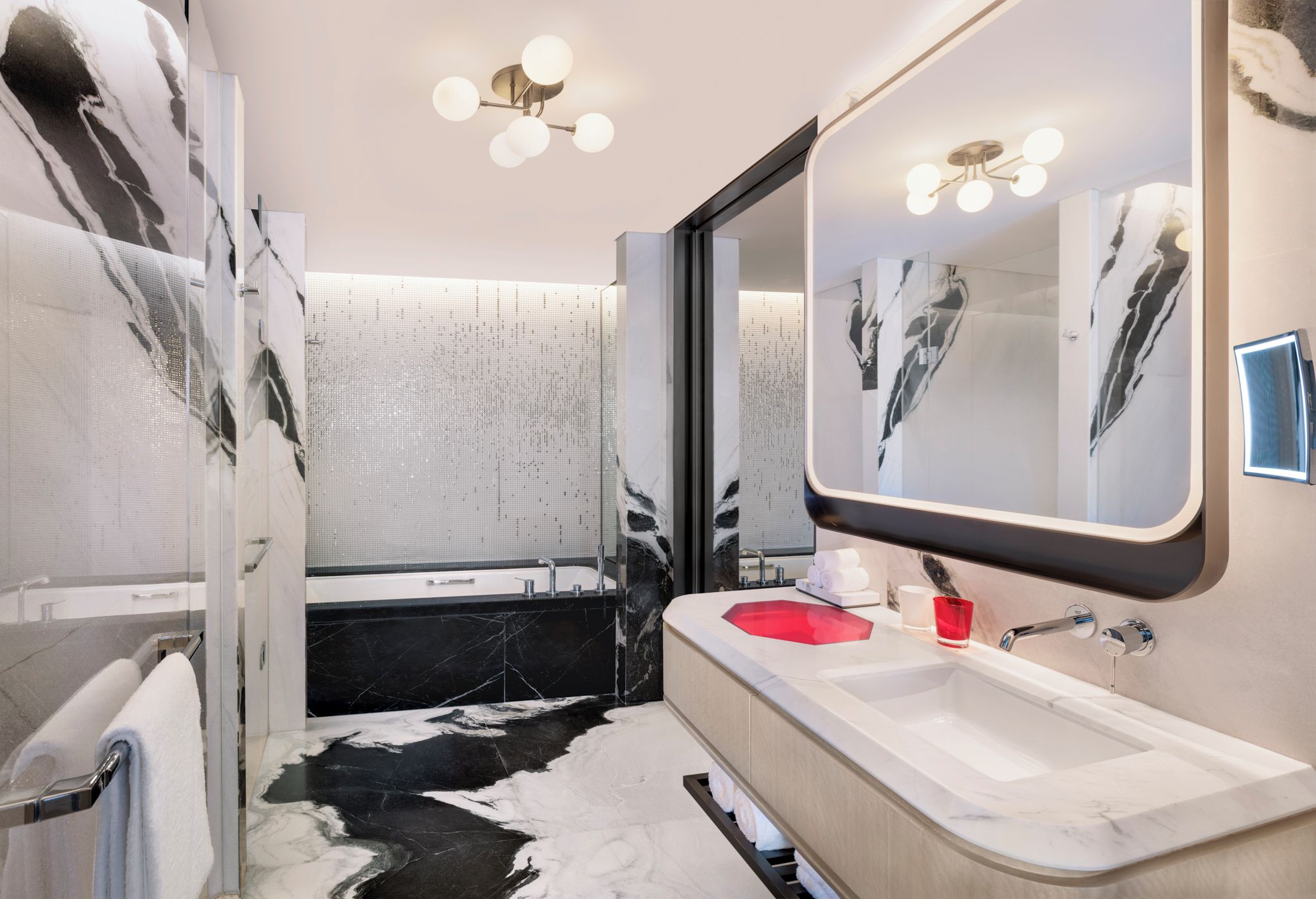 A modern bathroom with a large mirror, a bathtub, and a vanity with a sink.