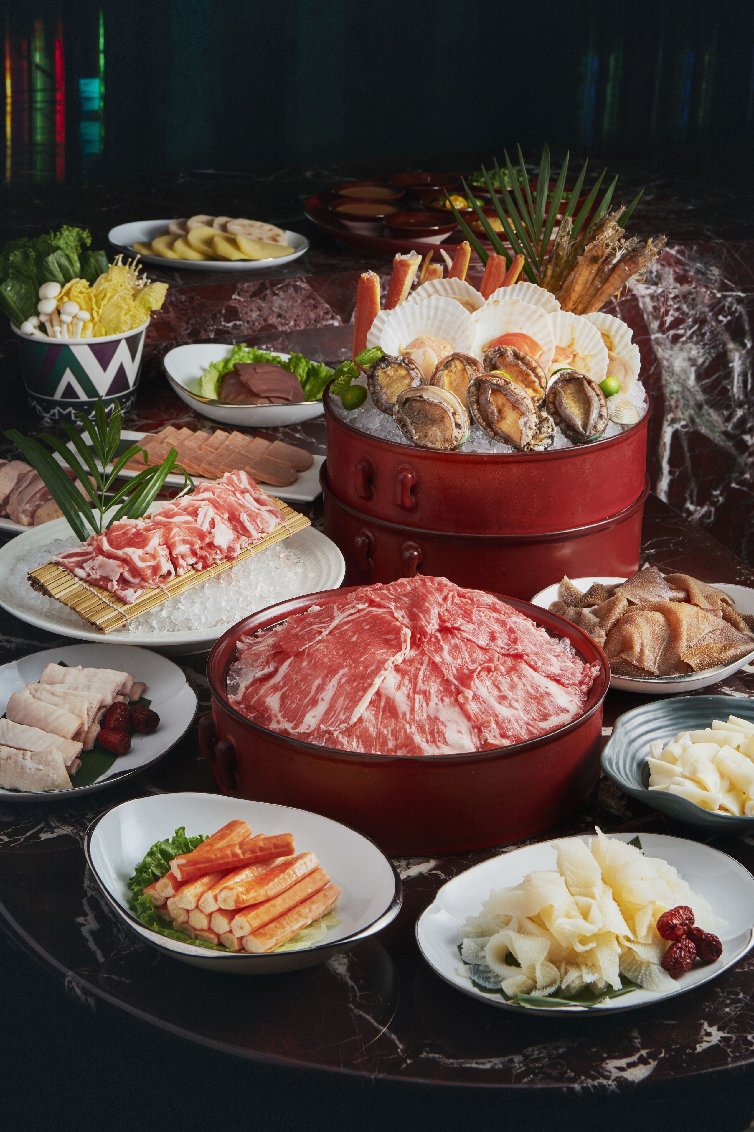 A variety of food items including meats, seafood, and vegetables arranged on a marble table.
