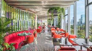 A modern restaurant with red seating, large windows, and a city view. - W Xiamen (Xiamen)