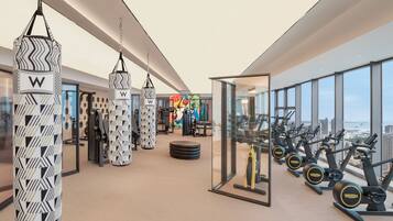 A modern gym with punching bags, exercise equipment, and a city view.