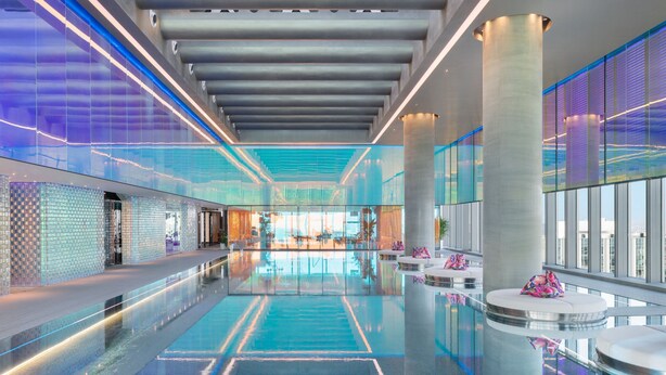 A modern hotel lobby with a reflective pool, glass railings, and a view of the cityscape. - W Xiamen (Xiamen)