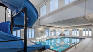 An indoor swimming pool with a blue slide, large windows, and a no diving sign. - TownePlace Suites by Marriott West Kelowna (West Kelowna)