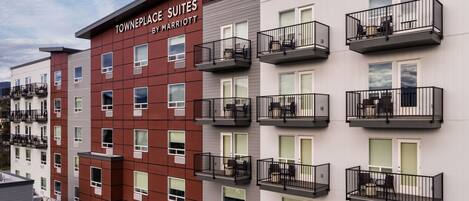 A multi-story hotel with 'Towneplace Suites by Marriott' signage, featuring balconies with outdoor furniture and a modern architectural design.