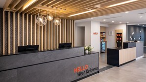 A reception area with a modern design, featuring a reception desk labeled "HELLO West Kelowna" and a "PINCH" sign in the background. - TownePlace Suites by Marriott West Kelowna (West Kelowna)