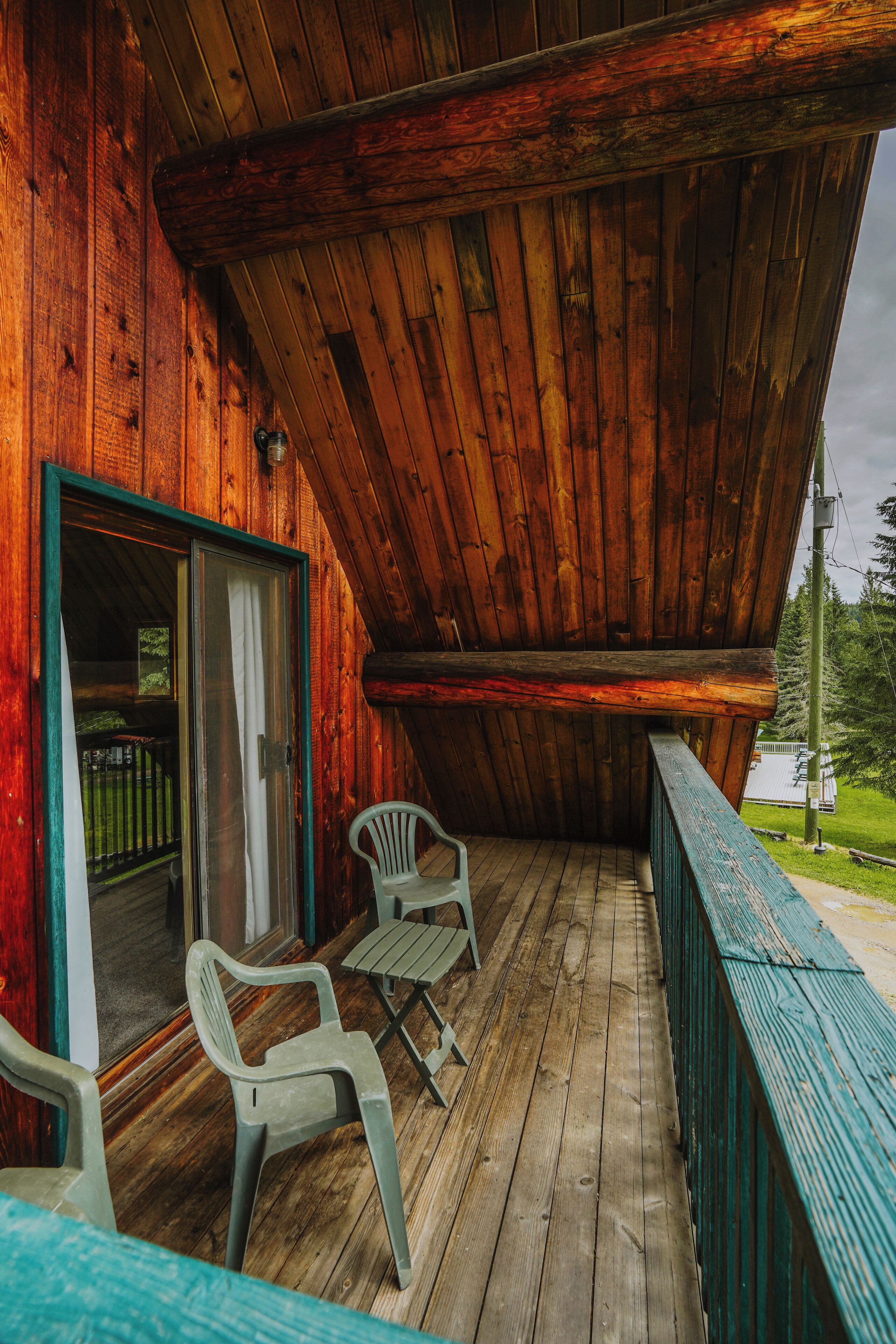 A wooden deck with two plastic chairs and a glass door leading to an interior space.