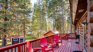 A wooden deck with red Adirondack chairs, a small wooden structure, and a forested backdrop. - 'The InnLet' - Comfy Cabin By Conkling Marina (Worley)