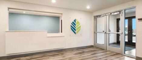 A spacious room with a wooden floor, a window, and a glass door leading outside.