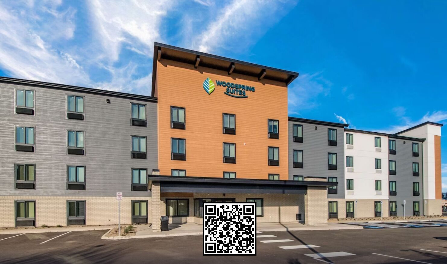 Un hotel de varios pisos con un letrero destacado que dice "Woodspring Suites".